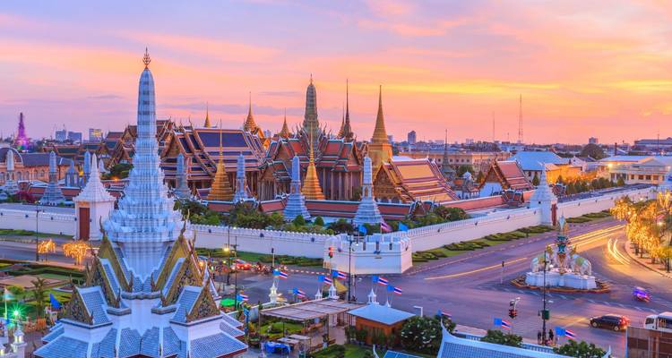 Sunset skyline of Bangkok featuring the Grand Palace and colourful spires against pastel skies.