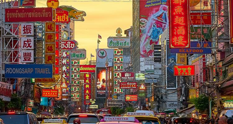 Bustling Yaowarat Road in Bangkok’s Chinatown filled with neon signs, traffic and street life at dusk.
