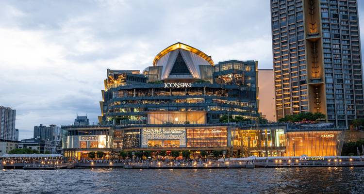 Uitzicht op de rivier op het verlichte ICONSIAM winkelcentrum in de schemering met spiegelingen in de Chao Phraya rivier.