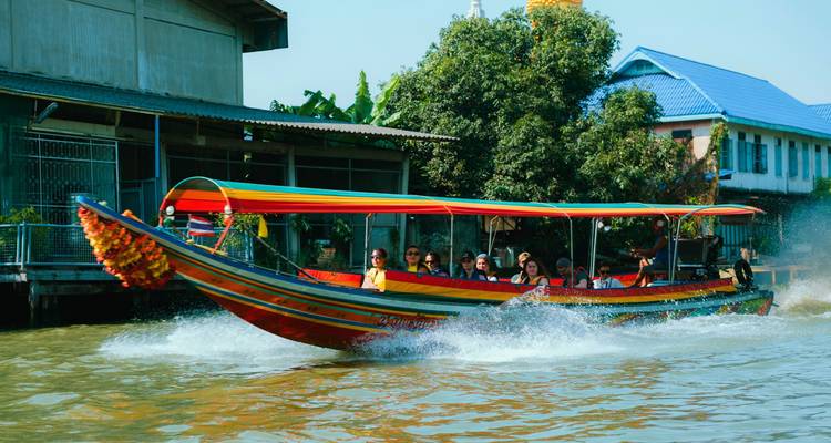Bateau à longue queue coloré fonçant à travers un canal, éclaboussant l'eau tandis que les touristes profitent de la promenade