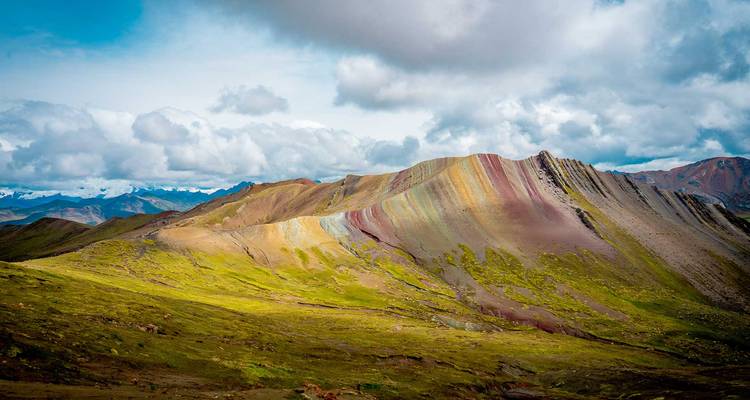 Levendige panoramische uitzicht op de veelkleurige bergrug van Rainbow Mountain onder dramatische wolken.