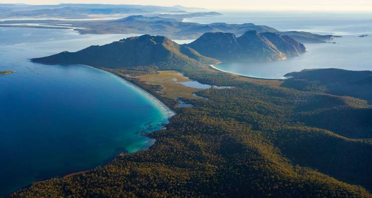 Une vue aérienne spectaculaire d'une péninsule boisée avec des baies turquoise, des montagnes escarpées et des îles au large entourées d'une eau océanique cristalline.