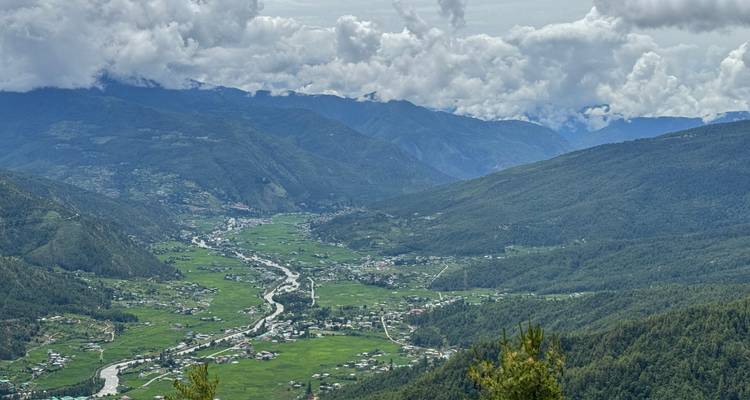 Weelderig groene Paro Valley die zich uitstrekt tussen bergketens onder dramatische wolken