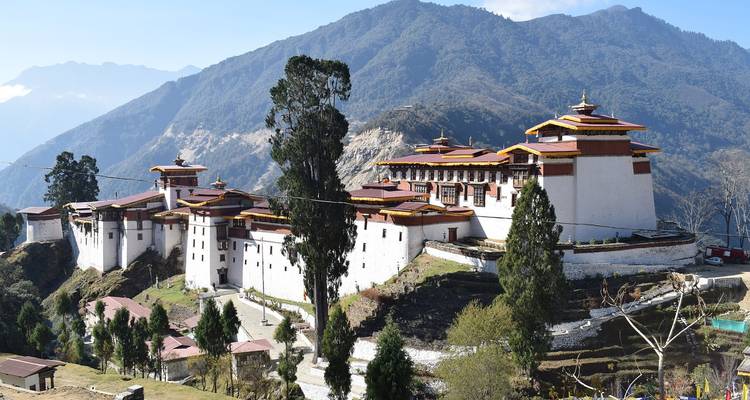 Lange Trongsa Dzong met witte muren troont op een bergrug tegen een bergachtergrond