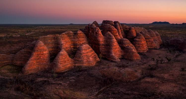Les dômes de grès en forme de ruches d'abeilles emblématiques brillent d'une teinte orange dans la faible lumière du crépuscule, s'élevant d'un paysage aride.