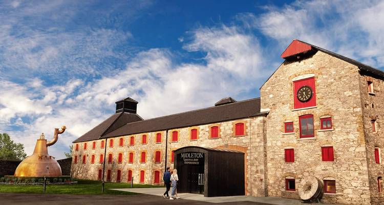 Les visiteurs se dirigeant vers la distillerie historique en pierre de Midleton avec le monument de l'alambic en cuivre.