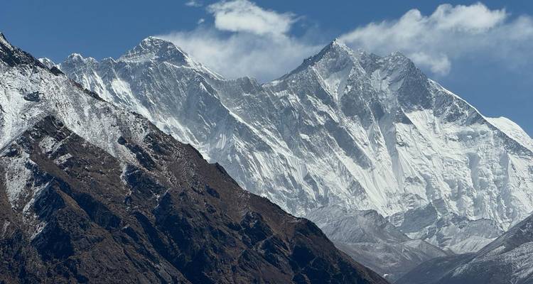 Breed bergpanorama van het Everest-massief met ruige bergkammen en sneeuwvelden tegen een helder lucht.