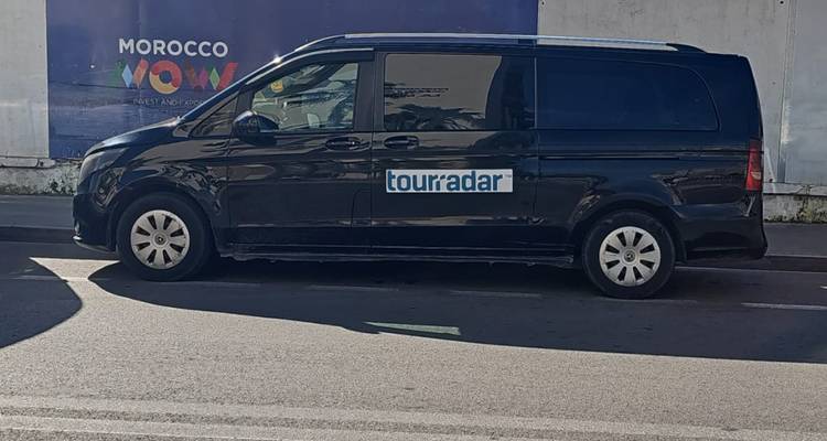 Fourgonnette noire de passagers avec l'identité visuelle de l'entreprise de tourisme stationnée le long d'une rue urbaine