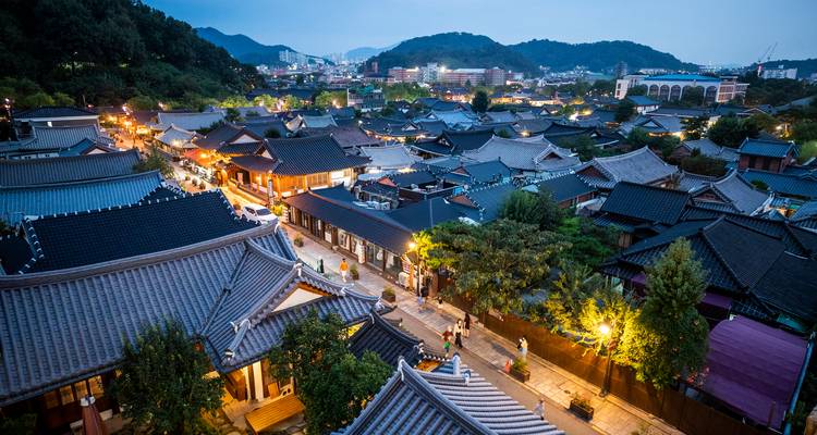 Vue en fin d'après-midi sur les toits du village Hanok de Jeonju brillant de lumières chaudes sur un fond de collines.