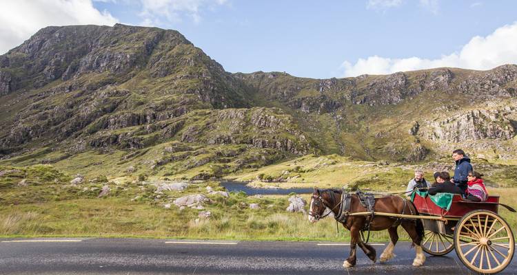 Voiture de tourisme tirée par des chevaux avec des visiteurs voyageant à travers les montagnes verdoyantes de la Ring of Kerry.