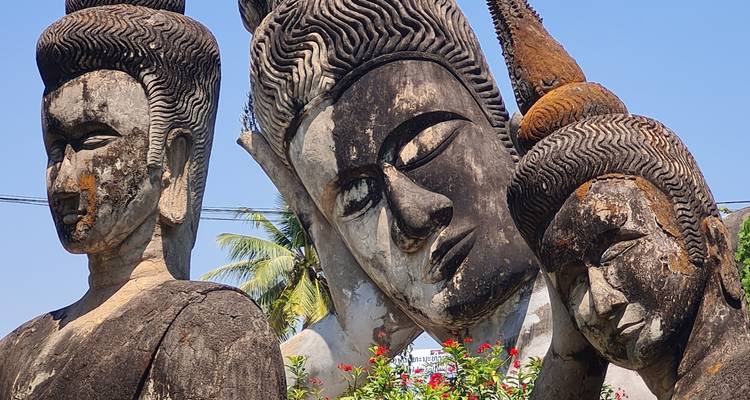 Les statues de Bouddha en béton usées se penchent ensemble sous le ciel bleu au Parc de Bouddha.