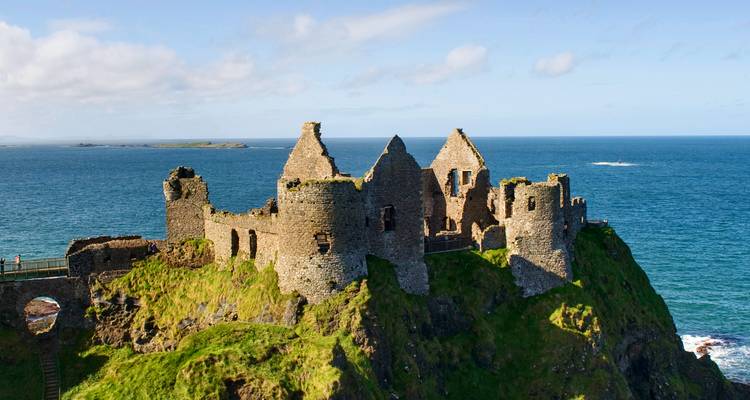 Dramatic ruins of Dunluce Castle perched atop cliffs overlooking the deep blue Atlantic Ocean
