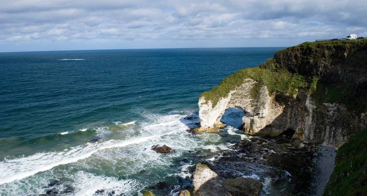 Rocky white sea arch and rugged coastline with turquoise waves crashing below