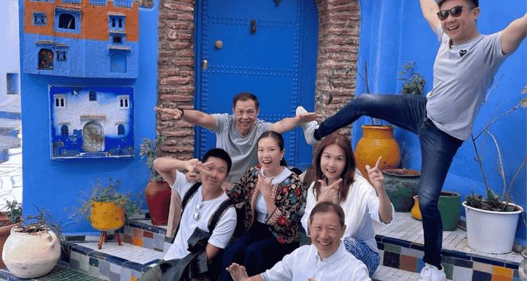 Des amis posent de manière ludique dans les rues peintes en bleu de Chefchaouen près d'une porte colorée.