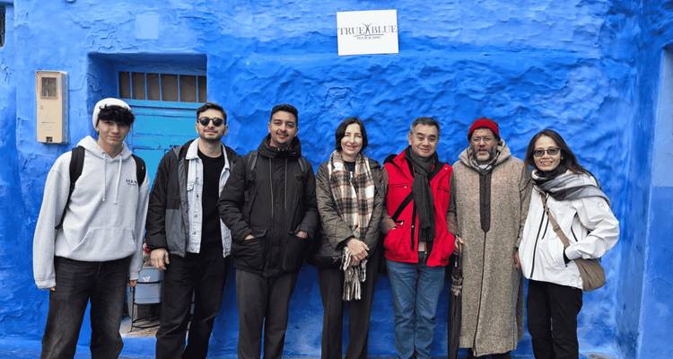 Les voyageurs se rassemblent contre un mur bleu éclatant de Chefchaouen avec une pancarte de visite au-dessus.
