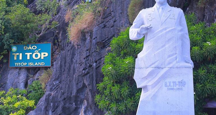 Statue en marbre d'un héros naval à côté d'une pancarte pour l'île de Ti Top devant une falaise rocheuse.