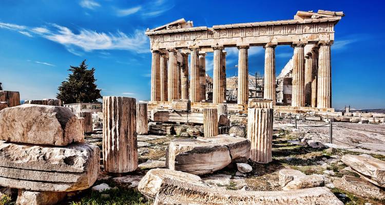 Ruins of the Parthenon with scattered marble columns under a deep blue Athens sky.