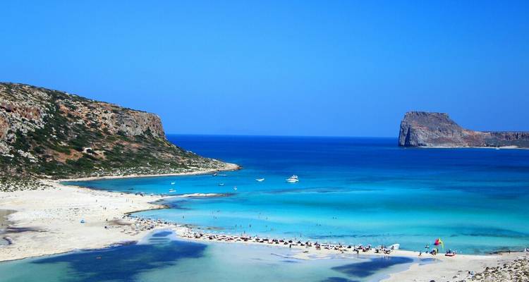 Turquoise lagoon and white sandbar with boats and swimmers at Balos Beach, Crete.