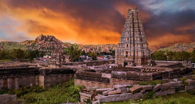Le temple Virupaksha s'élève au-dessus des ruines anciennes sous un ciel de coucher de soleil enflammé à Hampi.