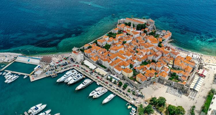 Luchtfoto van een versterkte Adriatische oude stad met terracotta daken, jachthavens en turquoise zee.