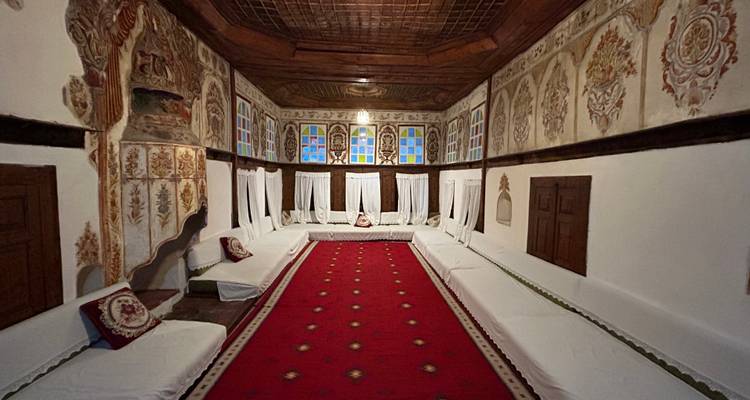 Een sierlijk ingerichte traditionele salon met gemusterde wanden, laag wit zitwerk en een lang rood tapijt.