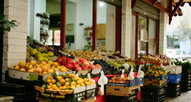 Een kleurrijke straatmarkt toont stapels verse fruit en groenten in plastic kratten.