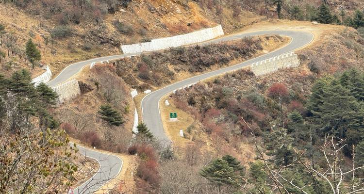 Een slingerende bergweg kronkelt zich door kale hellingen met scherpe haarspeldbochten.