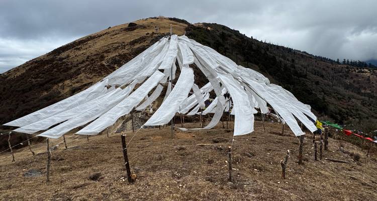 Witte gebedsvlaggen wapperen bovenop een kale bergrug tegen bewolkte hemel in het hooglland.