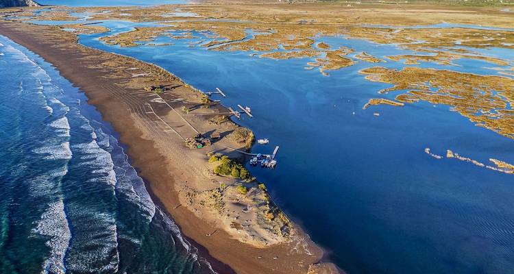 Dramatische luchtfoto van een zandplaat die zee en moeras scheidt met rollende golven.