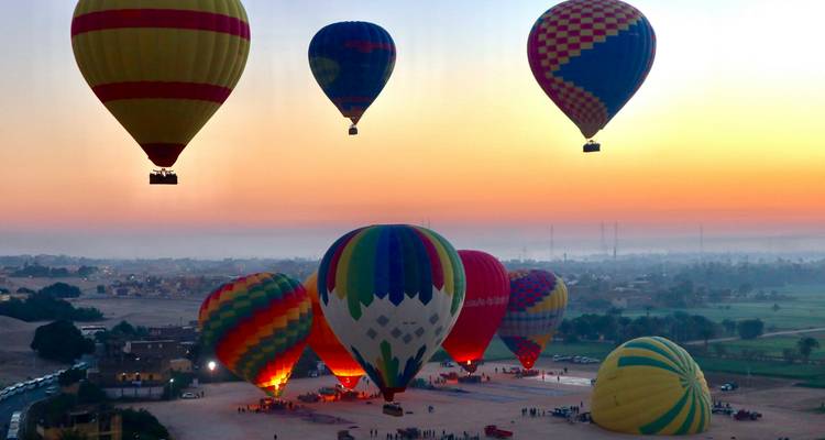 Des ballons à air chaud vibrants se gonflent et s'élèvent contre un ciel auroral resplendissant au-dessus de la vallée du Nil.