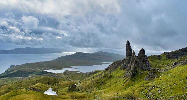 Pic rocheux et dramatique du Vieillard de Storr dominant les lochs et la mer sous un ciel nuageux et tourmenté.