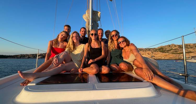 Neuf voyageurs heureux assis sur le pont d'un yacht sous un ciel d'un bleu éclatant