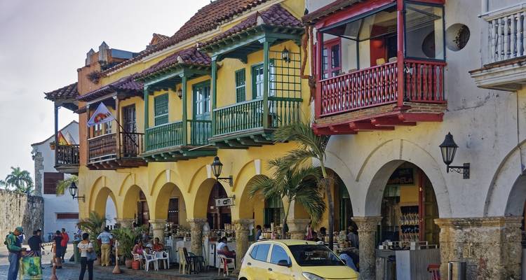 Colourful colonial balconies line a lively arcade where diners sit at outdoor tables.