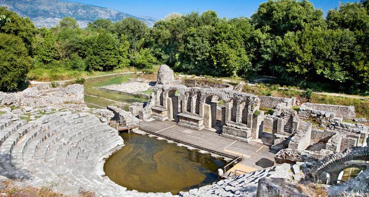 Théâtre antique bien préservé et ruines entourés de verdure dans le Parc national de Butrint.