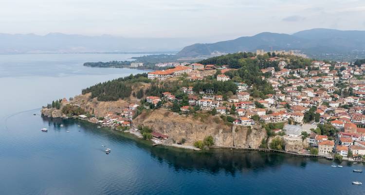 Vue aérienne d'une charmante petite ville au bord du lac avec des maisons aux toits rouges sur une péninsule rocheuse.