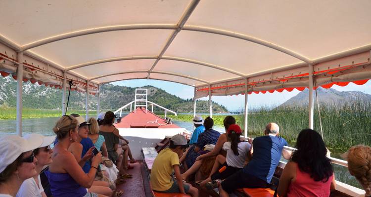 Touristen, die in einem überdachten Boot sitzen und durch Schilf und Seenlandschaften fahren