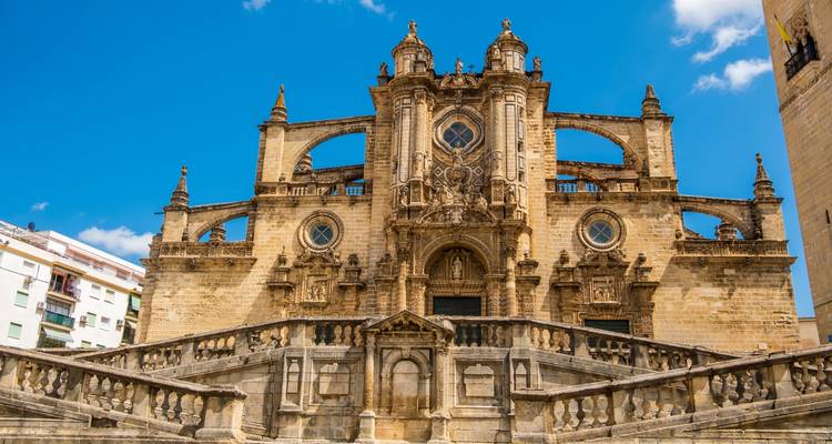 Façade baroque de la Cathédrale de Jerez encadrée par un grand escalier sur un ciel bleu profond.