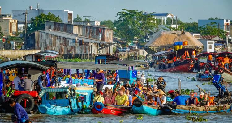Bustling floating market with colorful boats packed with produce and people on a wide river.