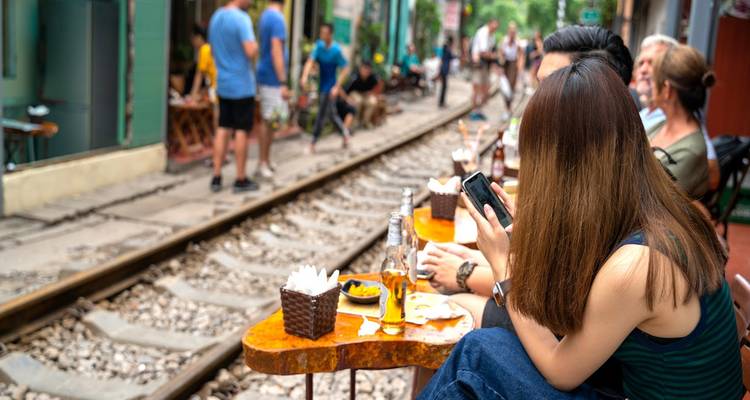 Los clientes del café se relajan tomando algo junto a la estrecha vía del tren en el barrio antiguo de Hanói.