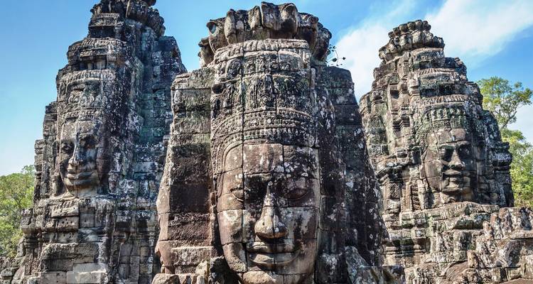 Los imponentes rostros de piedra del Templo Bayon en Angkor Thom recortados contra un cielo azul brillante.