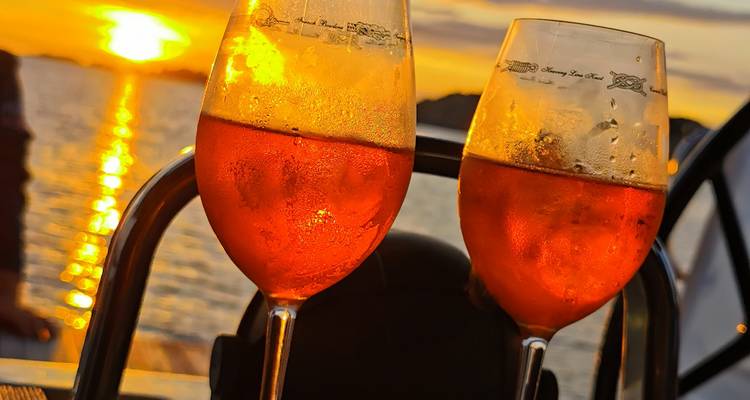 Two chilled orange cocktails glistening against a glowing sunset over the sea