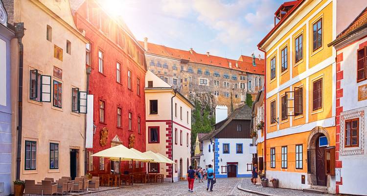 Ruelle pavée charmante à Cesky Krumlov avec des bâtiments aux couleurs vives, des cafés et le château dominant de haut.