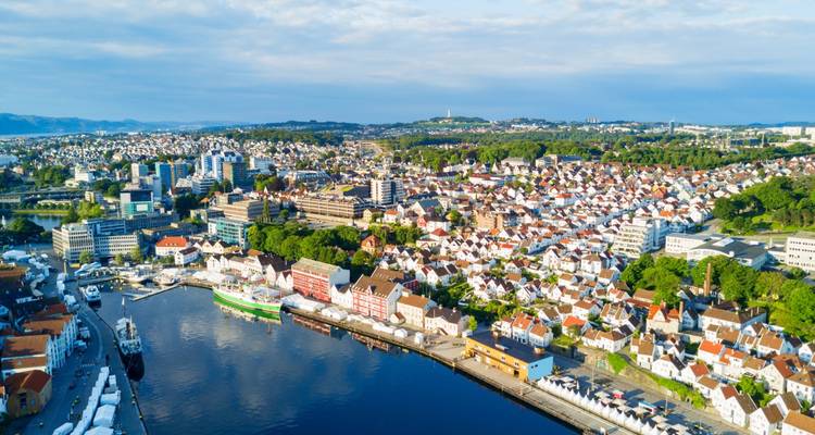 Vue aérienne large de Stavanger montrant son port, ses maisons blanches et ses collines verdoyantes par une journée ensoleillée.