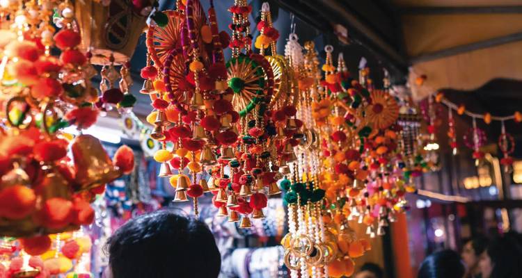 Brightly colored hanging ornaments fill a busy Indian market stall.
