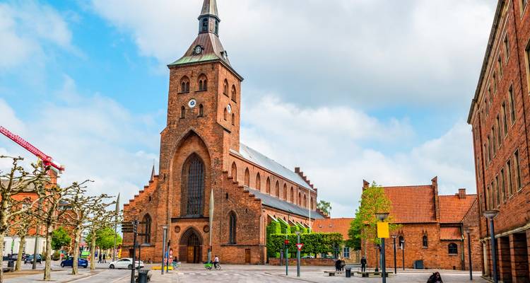 La cathédrale Sainte-Canute aux murs de brique rouge se dresse au-dessus de la place tranquille d'Odense par une journée ensoleillée.