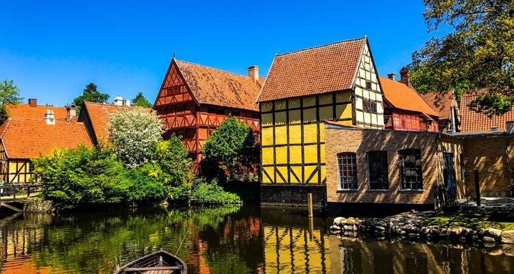 Des maisons historiques à colombages reflétées dans un canal tranquille du musée en plein air Den Gamle By d'Aarhus.