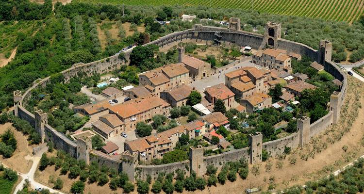 Luchtfoto van de perfect ronde middeleeuwse muren van Monteriggioni die stenen huizen en olijfgaarden omhullen.