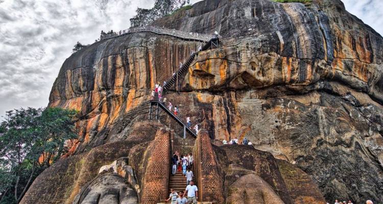 Visitors climbing staircases up the massive granite face and lion paw terrace of Sigiriya.