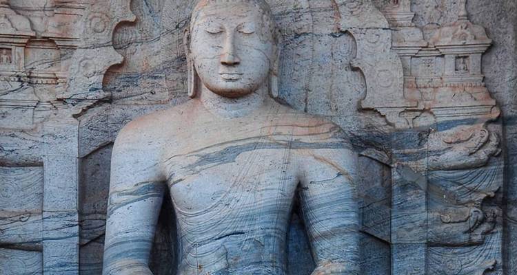 Close-up of an ancient stone-carved seated Buddha figure etched into a rock face