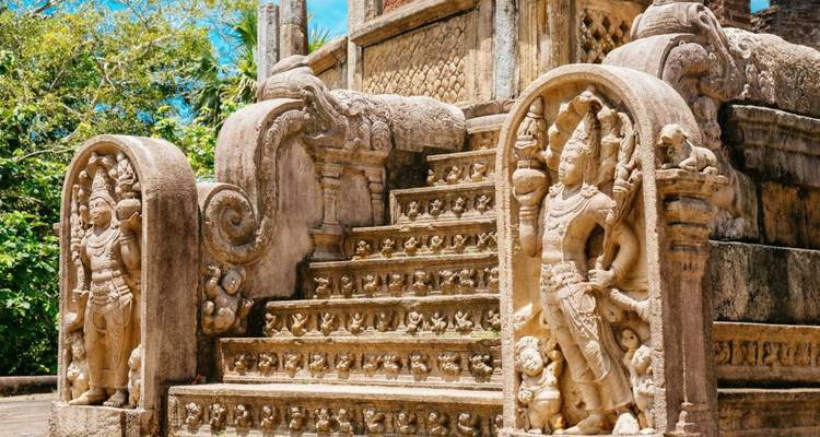 Intricately carved stone staircase with guardian figures and ornate moonstones at ancient ruins